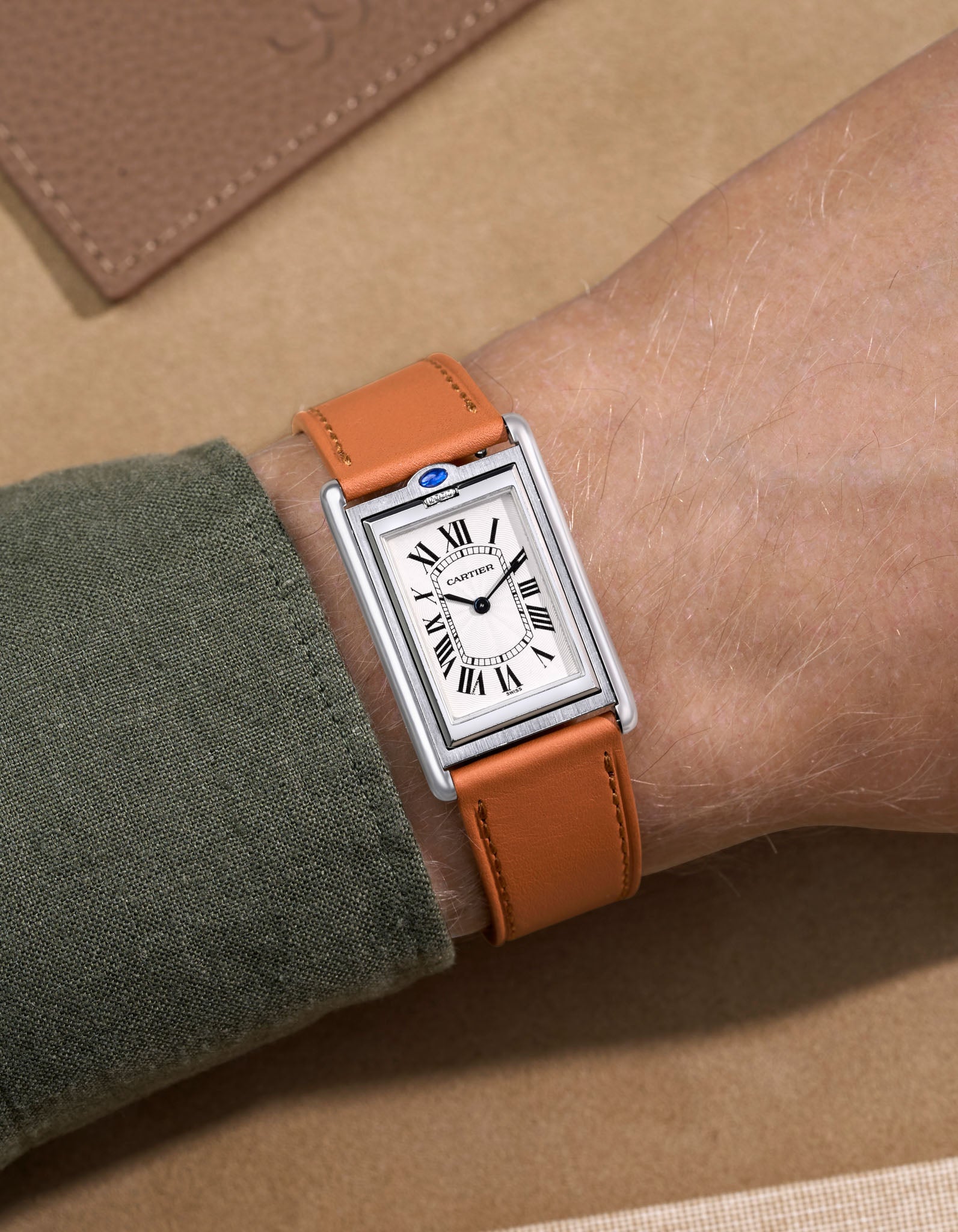 Cariter Basculante on a brown cowhide leather watch strap on a wrist with a suede background