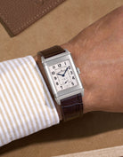 JLC Reverso steel watch with a dark brown embossed alligator leather watch strap on a beige background