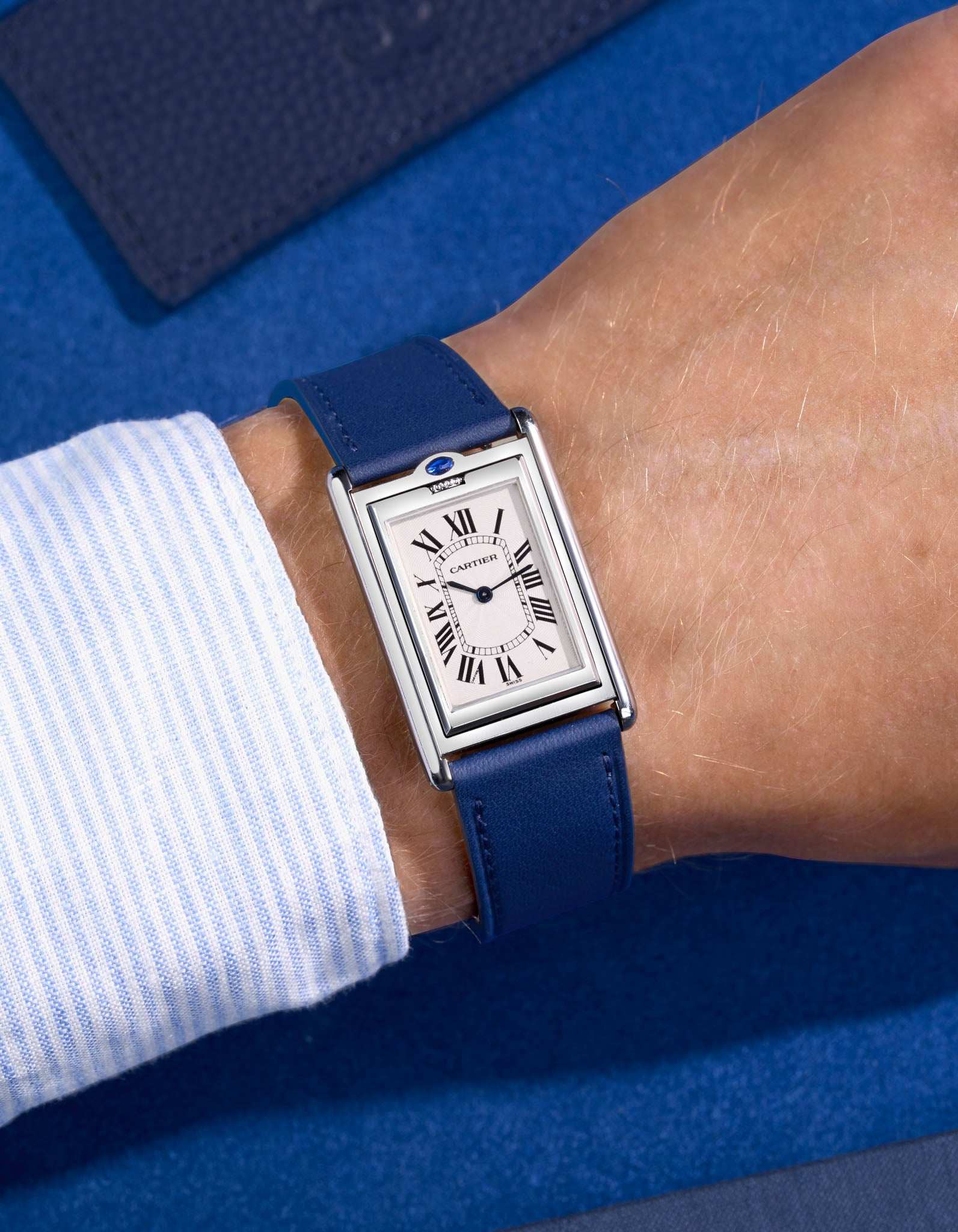cartier basculante with white dial and with a navy blue cowhide leather watch strap on a blue background