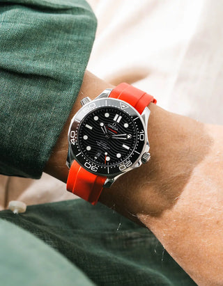 Red rubber strap for Omega Seamaster Diver 300 42mm – worn on wrist with dark green linen jacket, black dial and bezel, side angle view