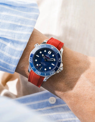 Red Vertech rubber strap for Omega Seamaster Diver 300 42mm – worn on wrist with light blue striped shirt, blue dial and bezel, front angle view