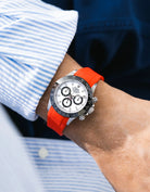Red integrated FKM rubber strap with original clasp on Rolex Daytona 116500 white dial ceramic bezel wrist shot with blue and white shirt