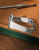 Beige textured integrated FKM rubber strap for Rolex Daytona 16520, fitted to original clasp, resting on a leather valet tray