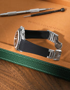 Black textured FKM rubber watch band for Rolex Daytona 16520, seamless case integration with original clasp, resting on a leather valet tray.