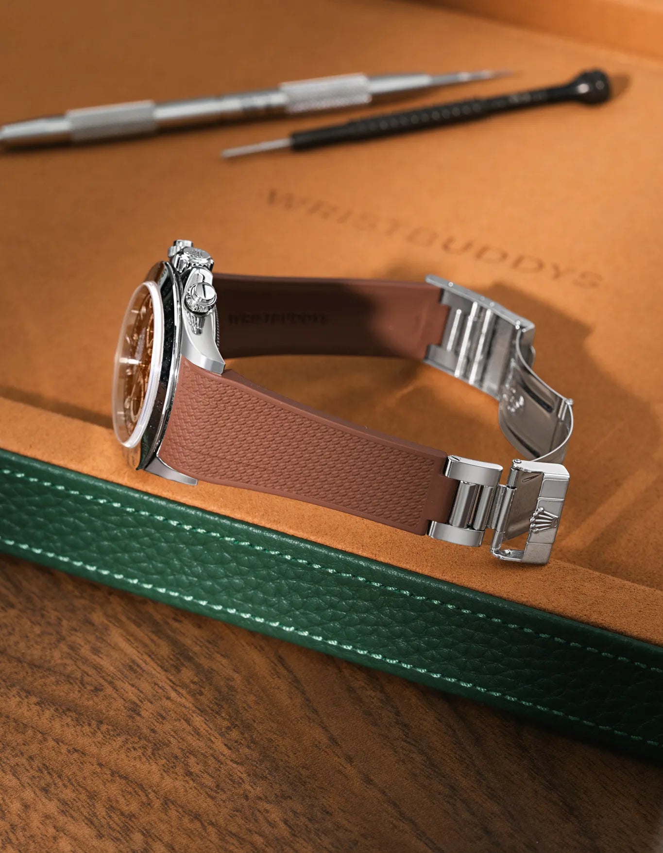 Brown Vertech FKM rubber watch band for Rolex Daytona 16520, custom integrated fit with original clasp, resting on a brown leather valet tray.