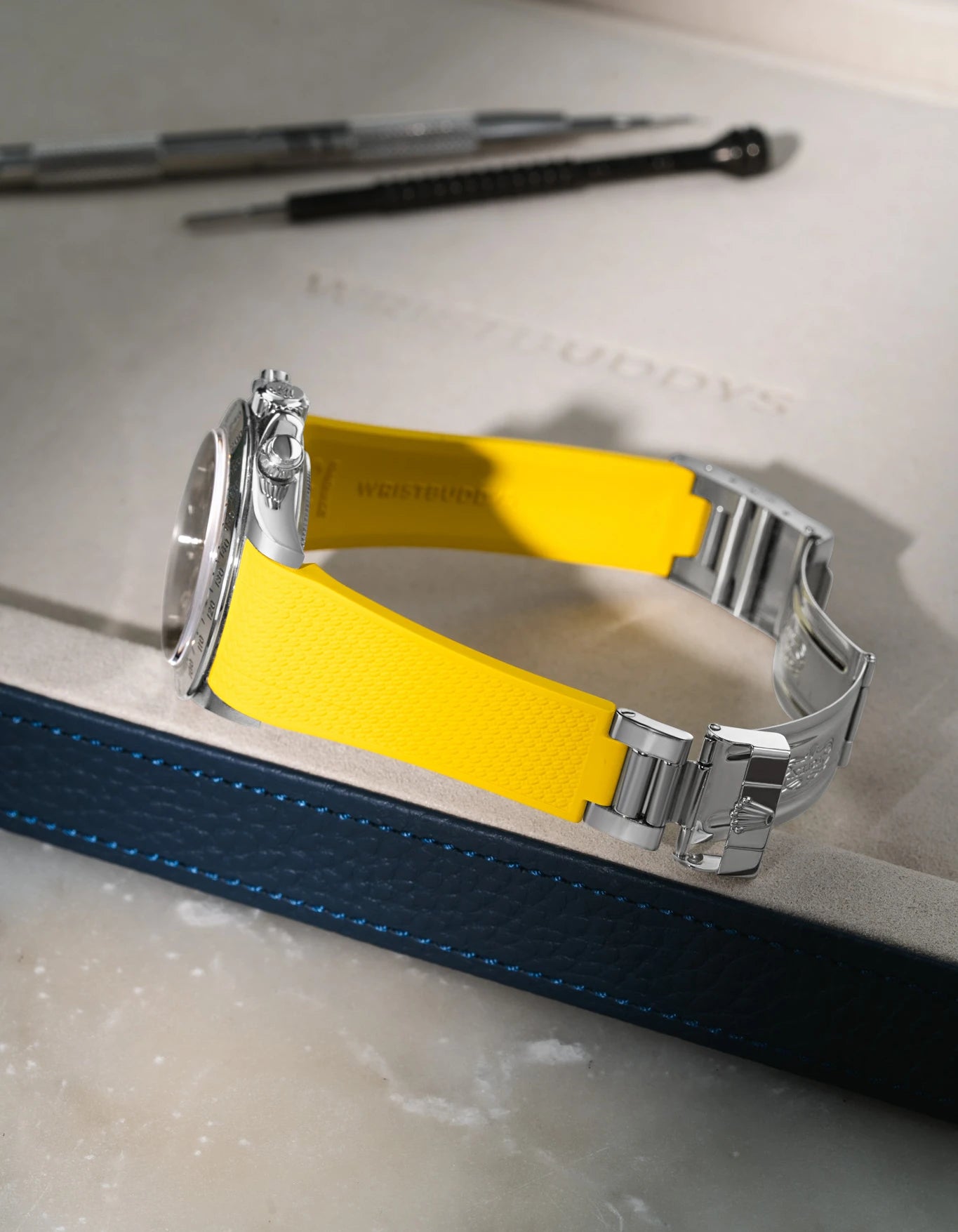 Yellow integrated FKM rubber watch band for Rolex Daytona 16520, textured finish with original clasp, resting on a white valet tray.