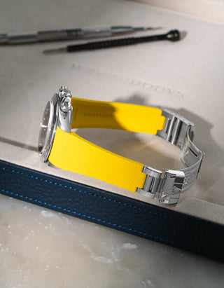 Yellow integrated FKM rubber watch band for Rolex Daytona 16520, textured finish with original clasp, resting on a white valet tray.