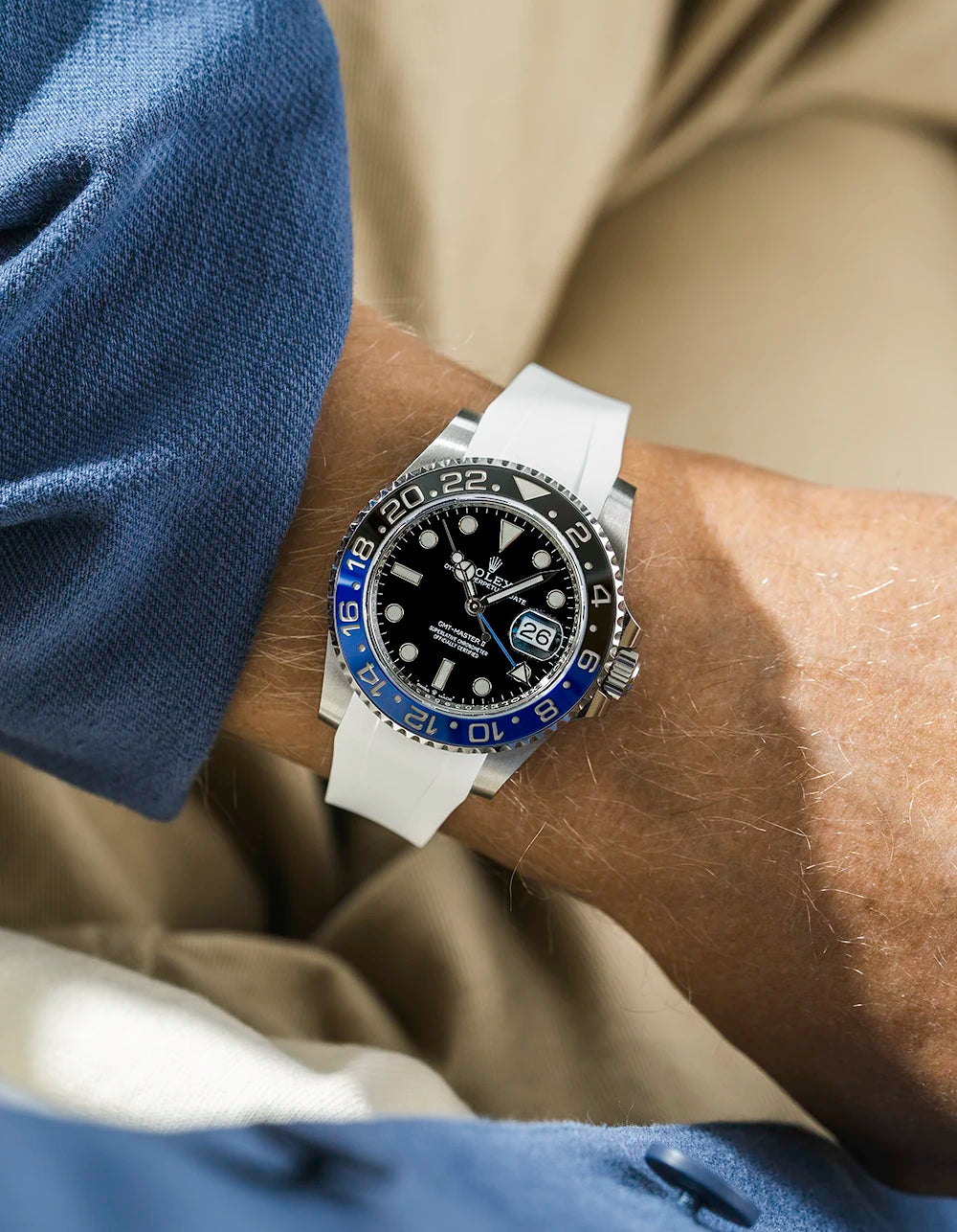 Close-up of a person wearing a Rolex GMT Master 2 batman model watch with a blue jacket sleeve and a white FKM rubber watch strap from Wristbuddys