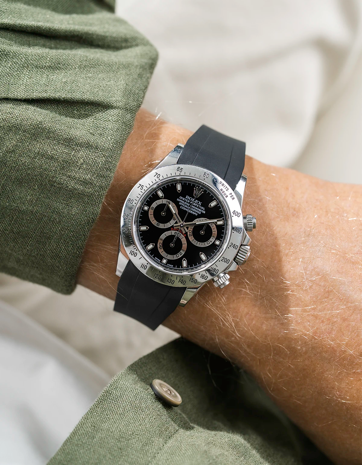 Close-up of a person wearing a black Rolex Daytona watch with a green jacket sleeve and a FKM rubber watch strap from Wristbuddys