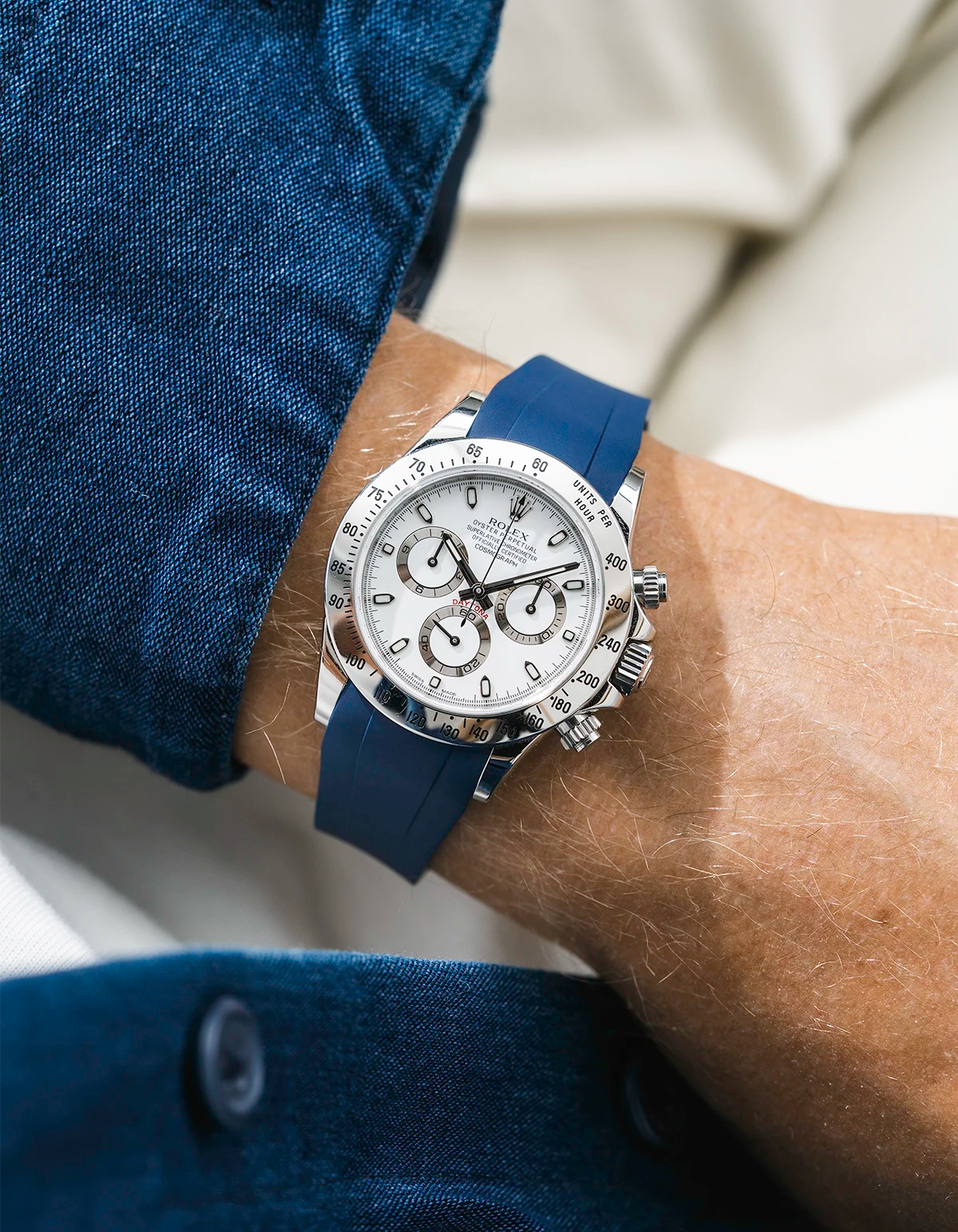 Close-up of a person wearing a white Rolex Daytona watch with a blue jacket sleeve and a FKM rubber watch strap from Wristbuddys