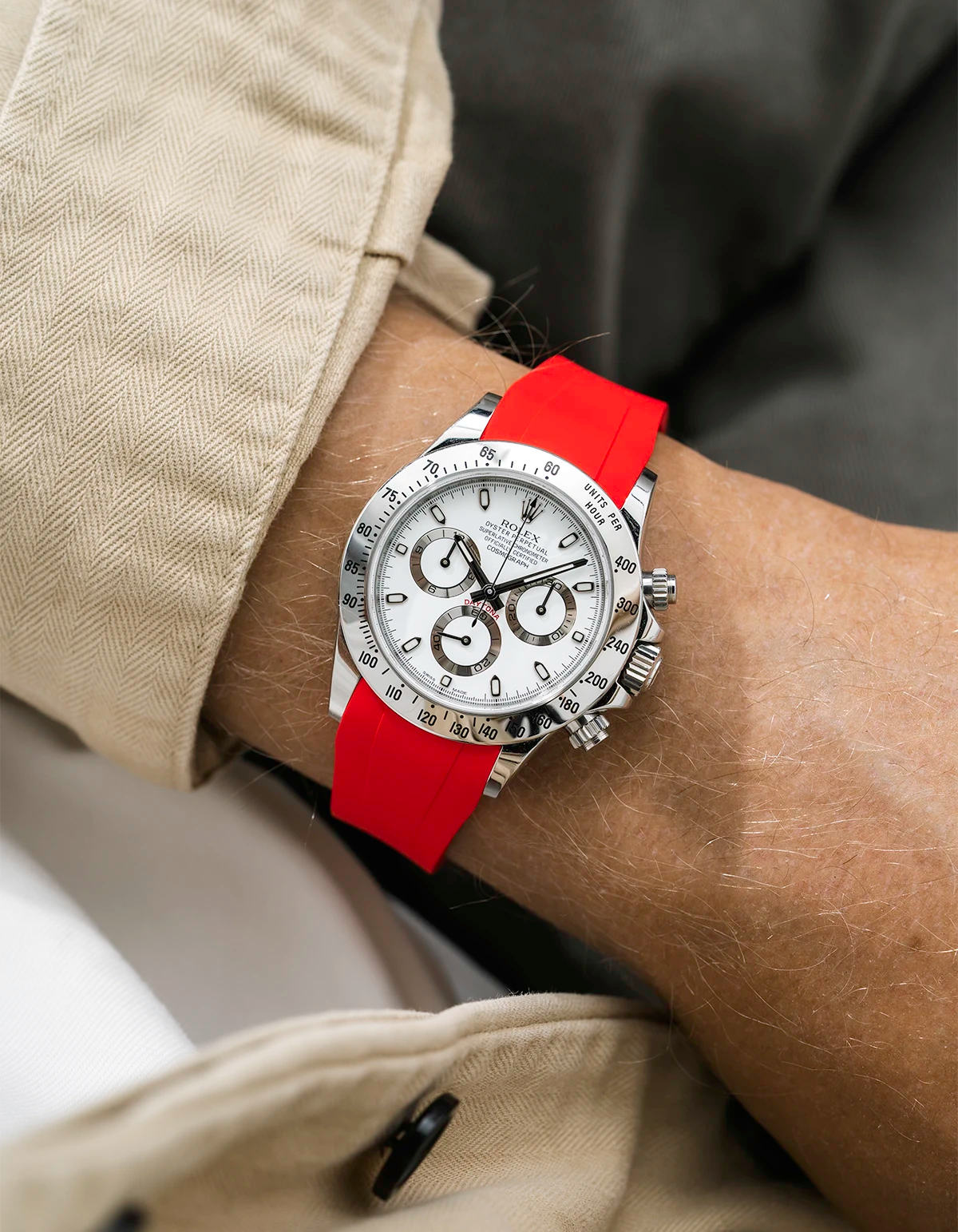 Close-up of a person wearing a white Rolex Daytona watch with a beige jacket sleeve and a red FKM rubber watch strap from Wristbuddys