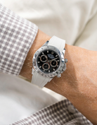Close-up of a person wearing a black Rolex Daytona watch with a beige white stiped shirt sleeve and a beige vertech FKM rubber watch strap from Wristbuddys