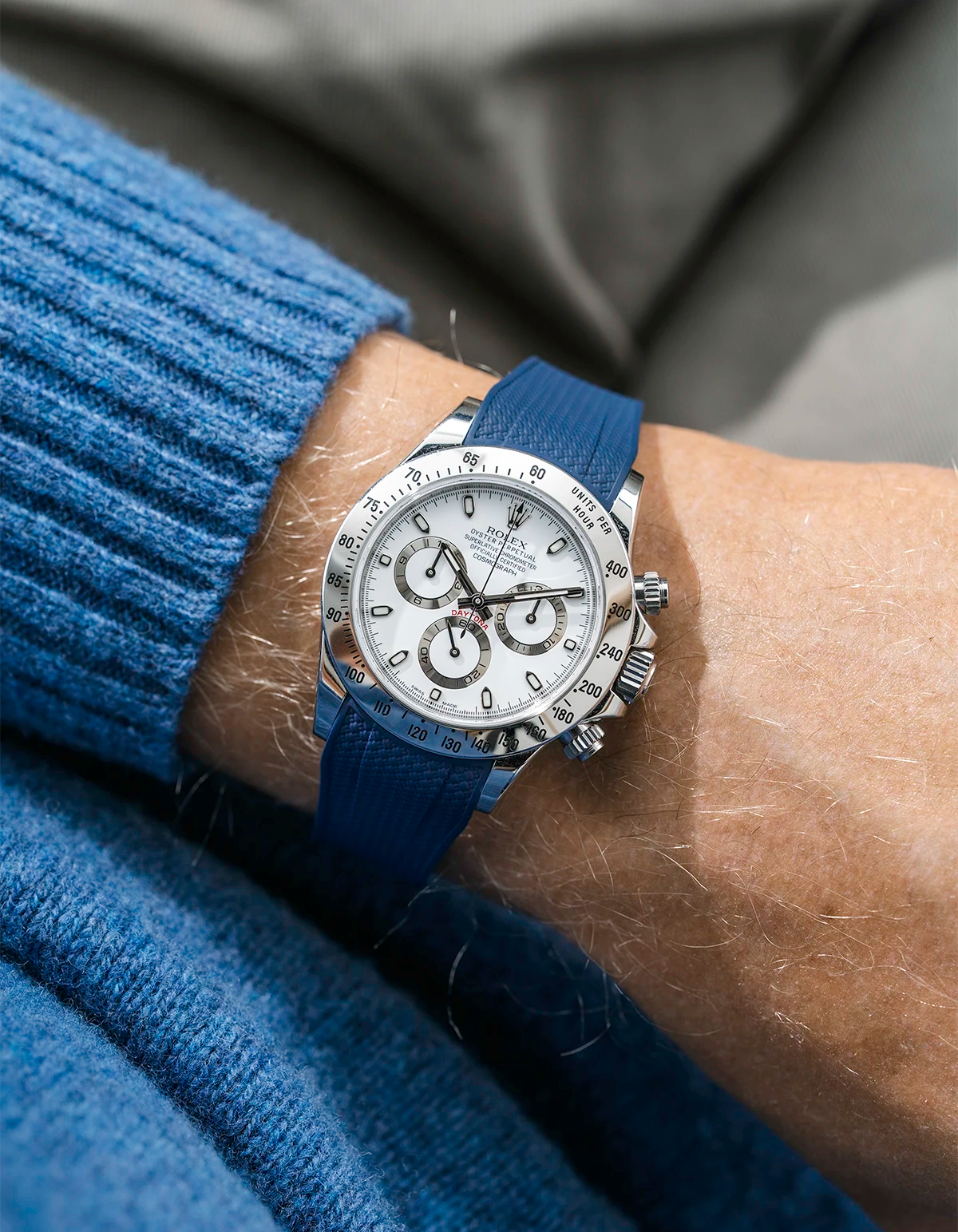 Close-up of a person wearing a white Rolex Daytona watch with a light blue stiped shirt sleeve and a dark blue vertech FKM rubber watch strap from Wristbuddys