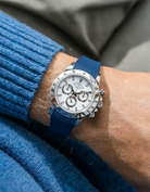 Close-up of a person wearing a white Rolex Daytona watch with a light blue stiped shirt sleeve and a dark blue vertech FKM rubber watch strap from Wristbuddys