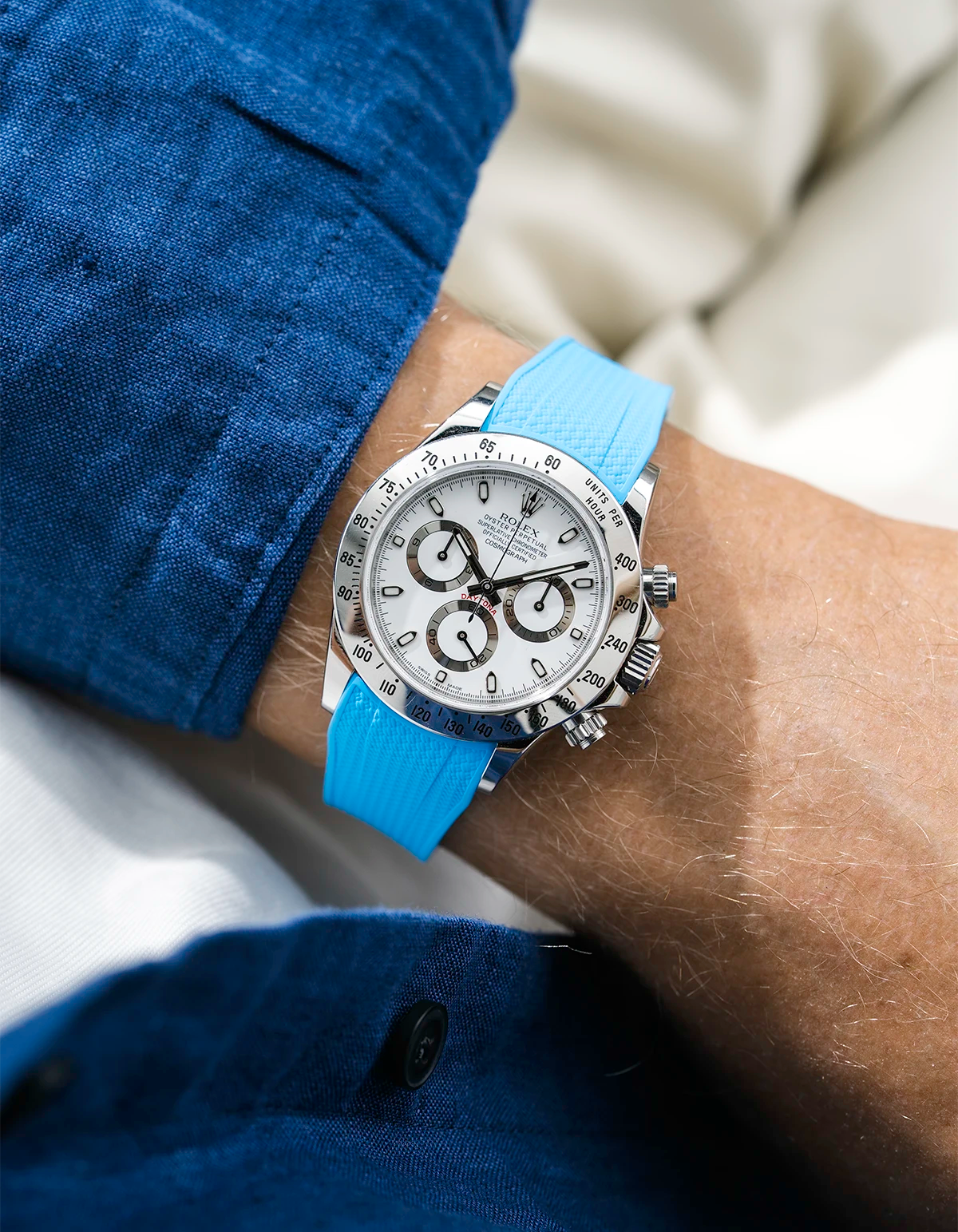 Close-up of a person wearing a white Rolex Daytona watch with a blue stiped shirt sleeve and a tuquoise vertech FKM rubber watch strap from Wristbuddys