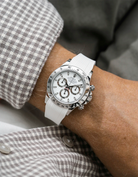 Close-up of a person wearing a white Rolex Daytona watch with a beige white stiped shirt sleeve and a white vertech FKM rubber watch strap from Wristbuddys