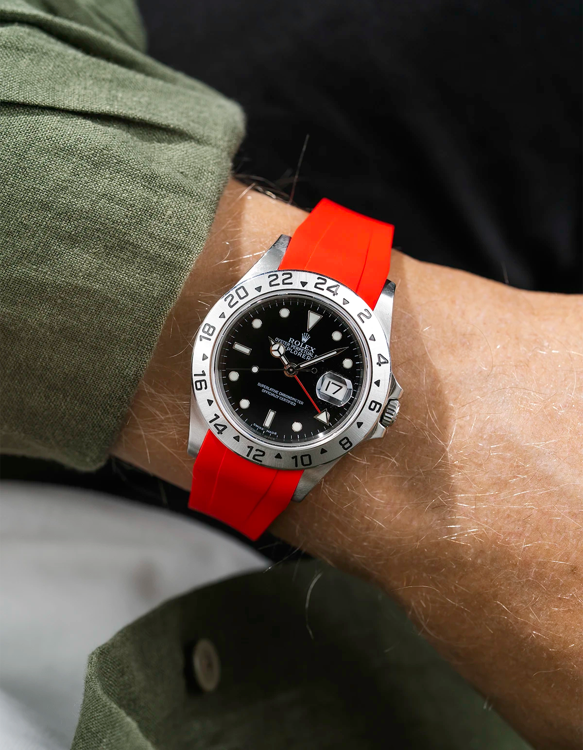 Close-up of a person wearing a Rolex Explorer 2 16570 model watch with a green jacket sleeve and a red FKM rubber watch strap from Wristbuddys