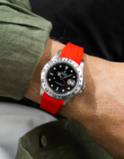 Close-up of a person wearing a Rolex Explorer 2 16570 model watch with a green jacket sleeve and a red FKM rubber watch strap from Wristbuddys