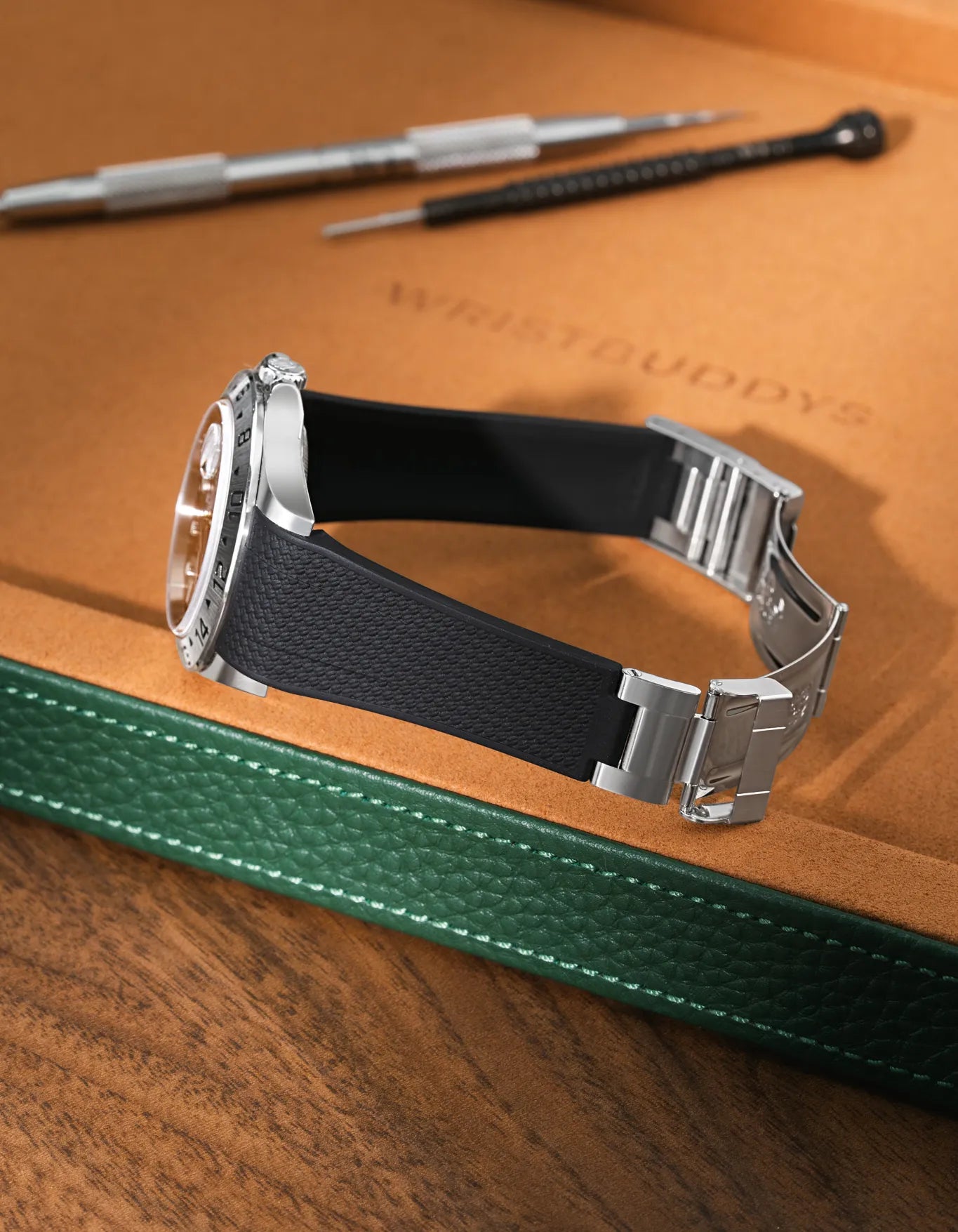 Black textured FKM rubber watch band for Rolex Explorer II 16570, seamless case integration, mounted with original clasp on a leather valet tray.