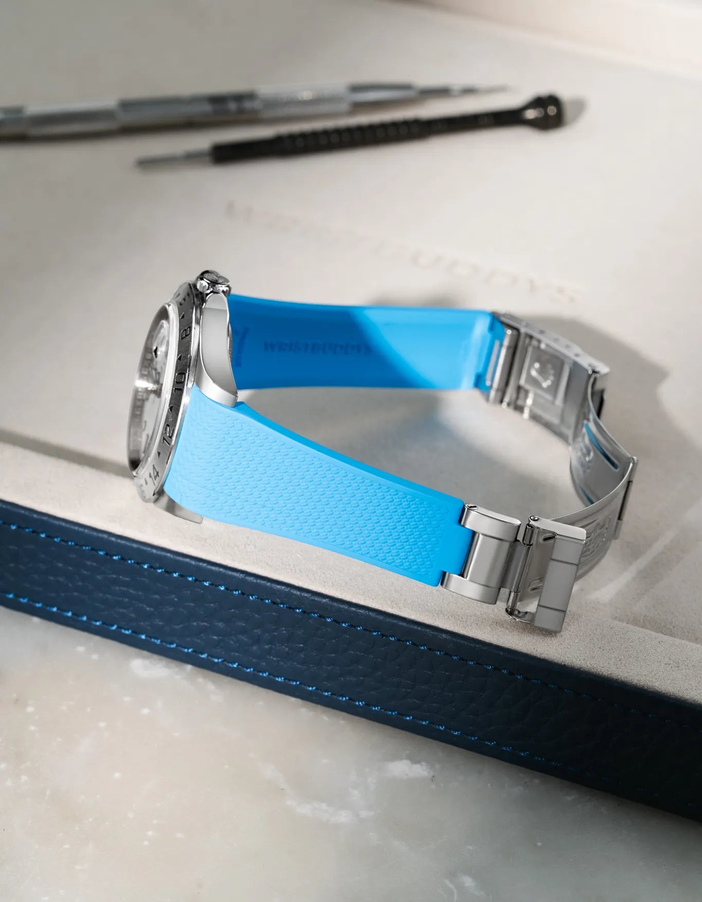 Capri Blue integrated FKM rubber watch strap for Rolex Explorer II 16570, Vertech textured finish, fits original clasp on a grey valet tray.