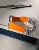 Orange textured FKM rubber watch band for Rolex Explorer II 16570, integrated design for original clasp, resting on a grey tray.