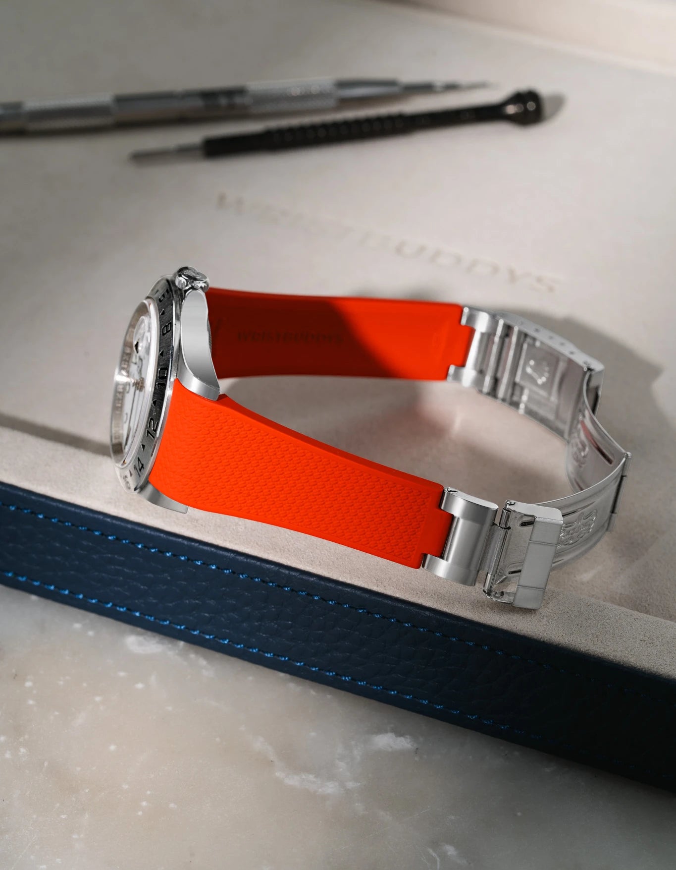 Red Vertech FKM rubber strap for Rolex Explorer II 16570, integrated seamless fit with original steel clasp, resting on a brown leather valet tray.