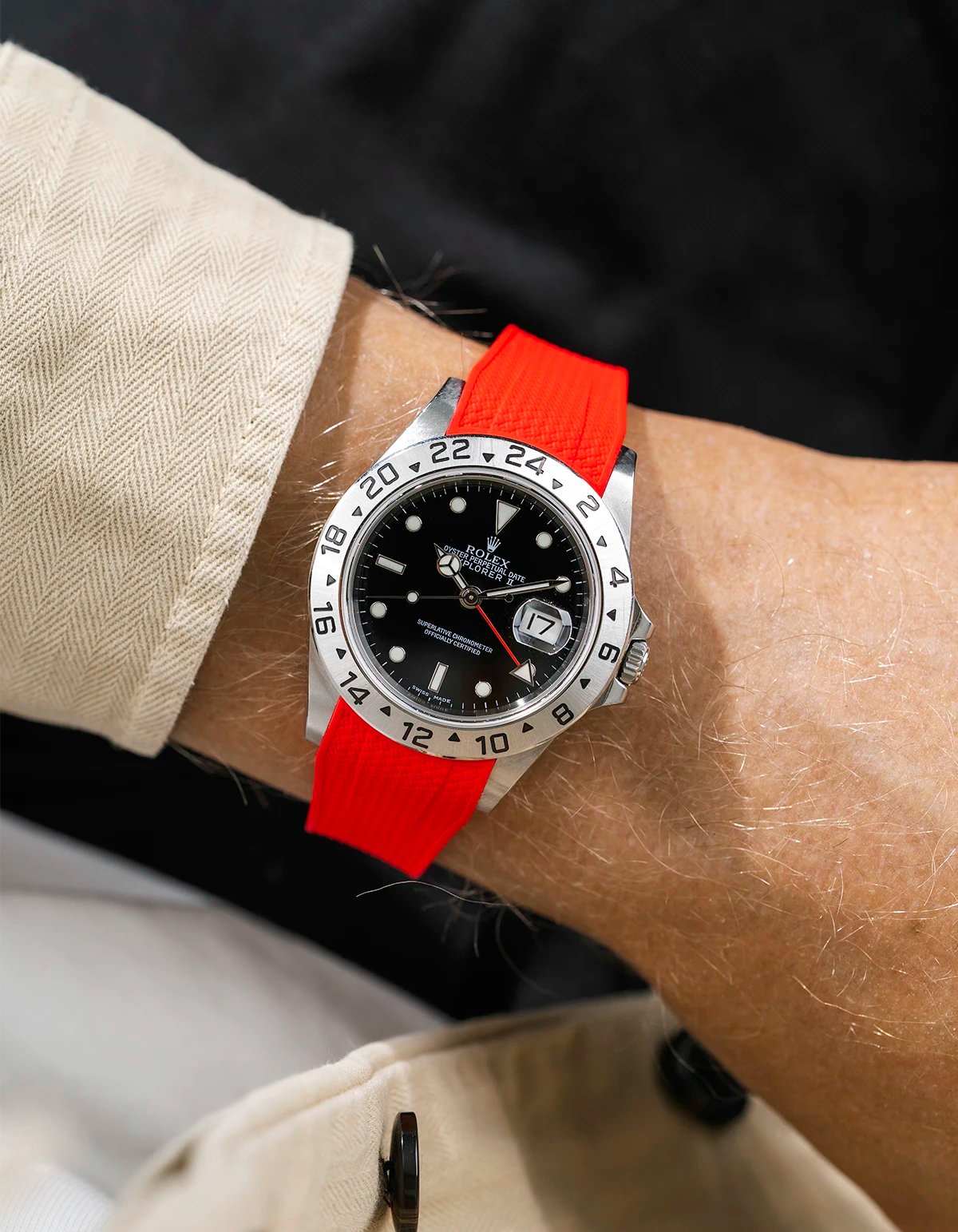 Close-up of a person wearing a Rolex Explorer 2 16570 model watch with a beige jacket sleeve and a red Vertech FKM rubber watch strap from Wristbuddys