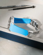 Capri Blue integrated FKM rubber watch strap for Rolex GMT-Master II 116710, Vertech textured finish, fits original clasp on a grey valet tray.