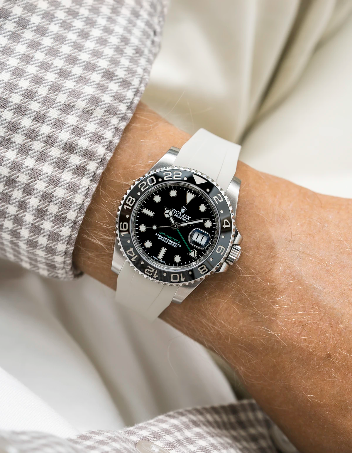 Close-up of a person wearing a Rolex GMT Master Green hand 116710 model watch with  white and beige jacket sleeve and a beige FKM rubber watch strap from Wristbuddys