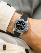 Close-up of a person wearing a Rolex GMT Master Green hand 116710 model watch with  beige jacket sleeve and a black FKM rubber watch strap from Wristbuddys