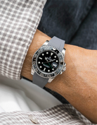 Close-up of a person wearing a Rolex GMT Master Green hand 116710 model watch with  white and beige jacket sleeve and a grey FKM rubber watch strap from Wristbuddys