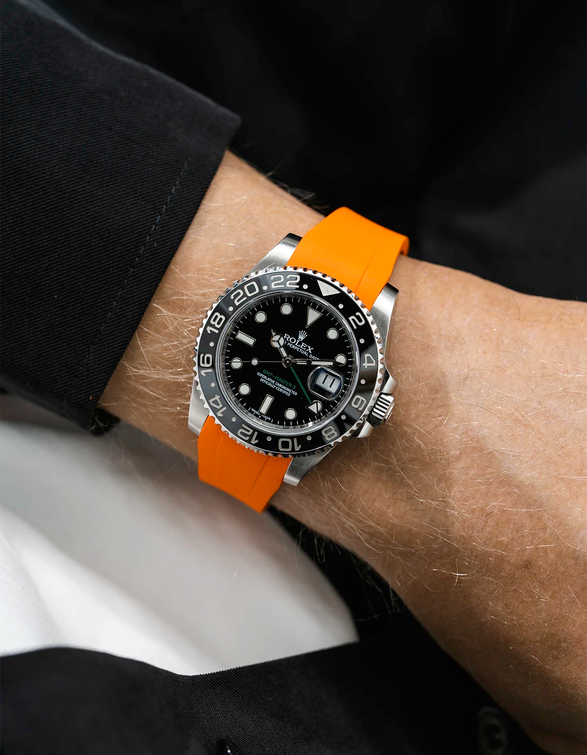 Close-up of a person wearing a Rolex GMT Master Green hand 116710 model watch with  black jacket sleeve and a orange FKM rubber watch strap from Wristbuddys