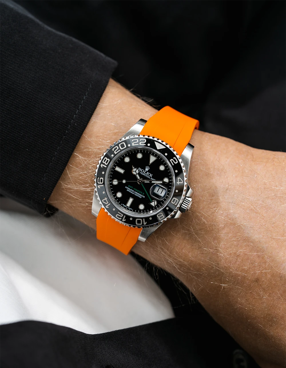 Close-up of a person wearing a Rolex GMT Master Green hand 116710 model watch with  black jacket sleeve and a orange FKM rubber watch strap from Wristbuddys