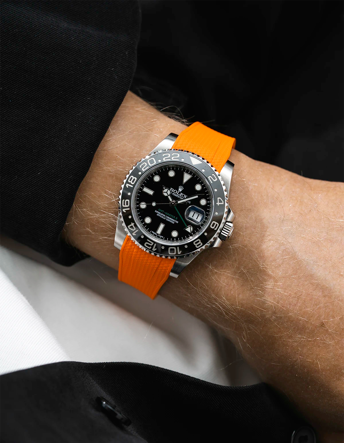 Close-up of a person wearing a Rolex GMT Master Green hand 116710 model watch with black jacket sleeve and a orange vertech FKM rubber watch strap from Wristbuddys