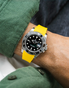 Close-up of a person wearing a Rolex GMT Master Green hand 116710 model watch with green jacket sleeve and a yellow vertech FKM rubber watch strap from Wristbuddys