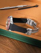 Black Vertech FKM rubber strap for Rolex GMT Master II 116710/126710, integrated seamless fit with original clasp, resting on a leather valet tray.