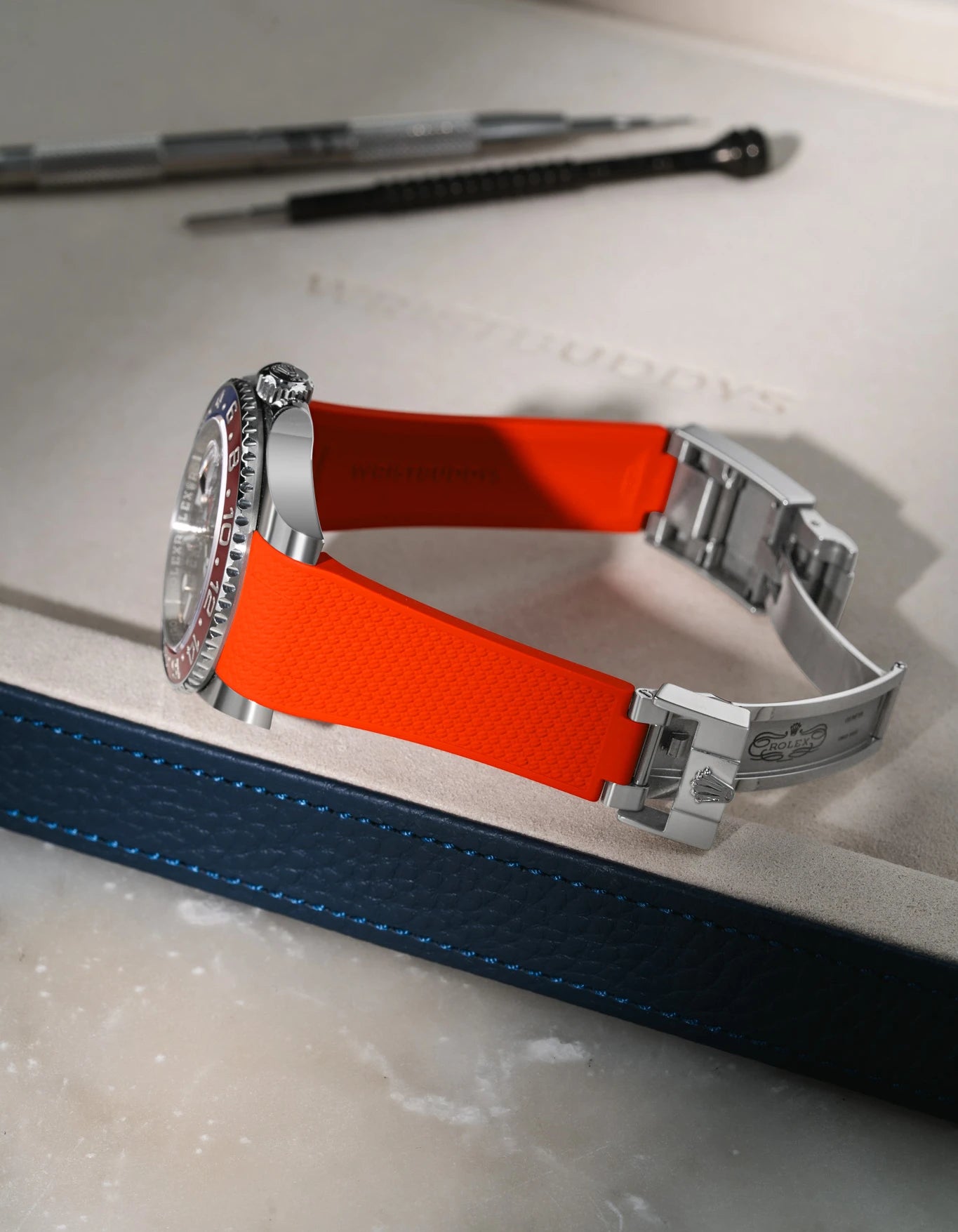 Red Vertech FKM rubber strap for Rolex GMT Master II 116710/126710, integrated design for original clasp, shown on a premium leather valet tray.