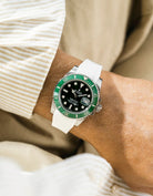 Close-up of a wrist wearing a Rolex Submariner on a Wristbuddys FKM Rubber watch strap and white strap with a blurred background