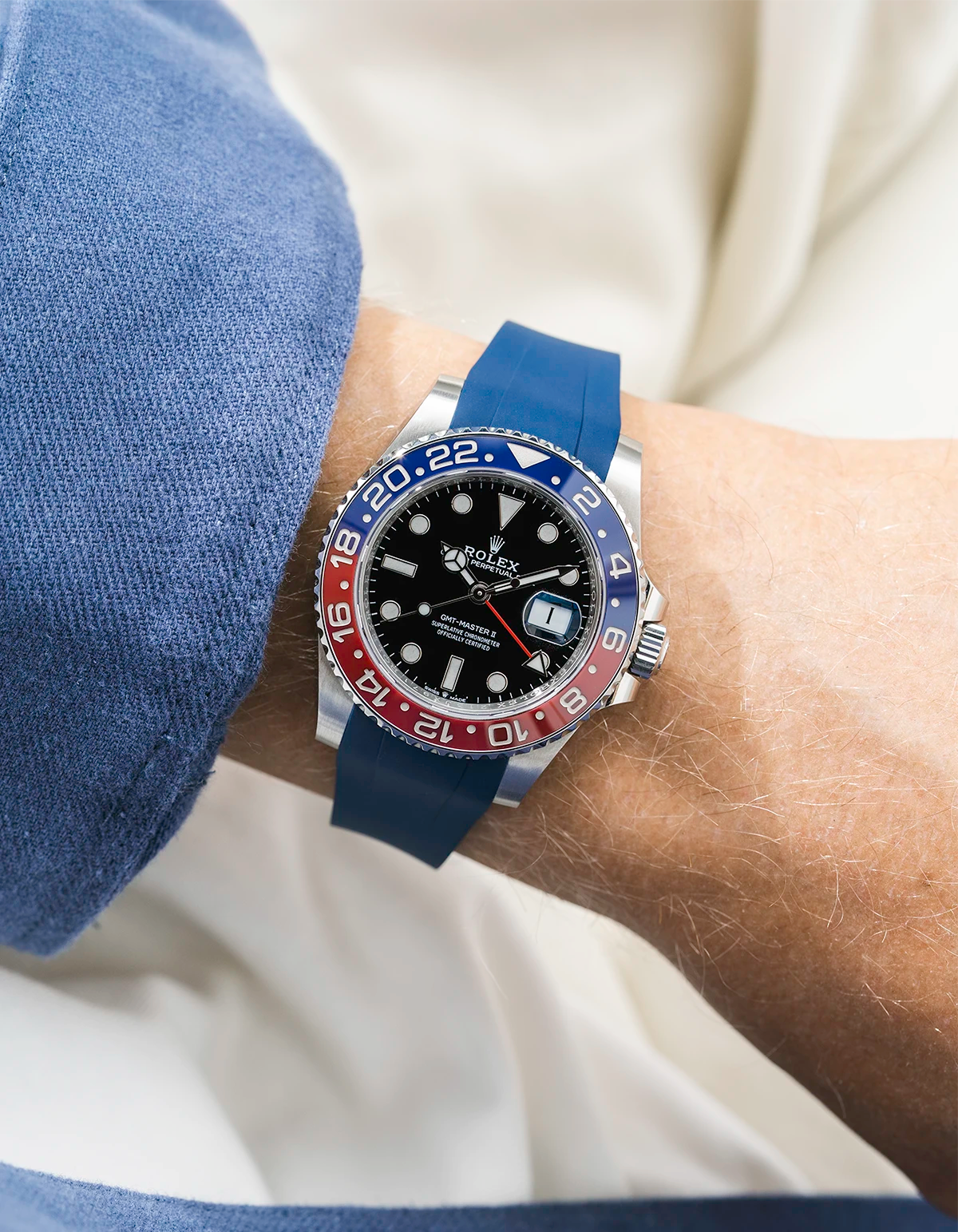 Close-up of a person wearing a Rolex GMT Master 2 Pepsi model watch with a blue jacket sleeve and a blue FKM rubber watch strap from Wristbuddys