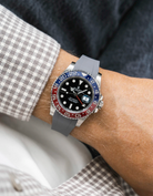 Close-up of a person wearing a Rolex GMT Master 2 Pepsi model watch with a beige white jacket sleeve and a grey FKM rubber watch strap from Wristbuddys