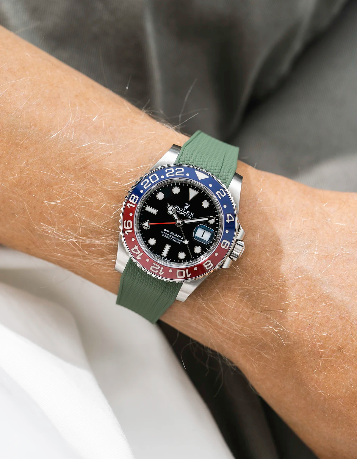 Close-up of a person wearing a Rolex GMT Master 2 Pepsi model watch with  sleeve and a green vertech FKM rubber watch strap from Wristbuddys