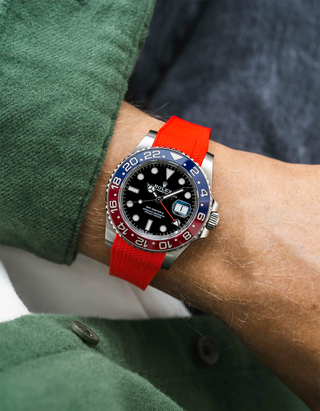 Close-up of a person wearing a Rolex GMT Master 2 Pepsi model watch with  green jacket sleeve and a red vertech FKM rubber watch strap from Wristbuddys