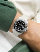 White watch with Rolex Submariner on a beige Wristbuddys FKM Rubber watch strap wearing a green sleeve.