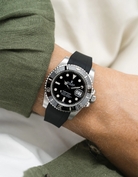 Black Rolex Submariner on a Wristbuddys FKM Rubber watch strap with a silver case on a person's wrist, wearing a green sleeve.