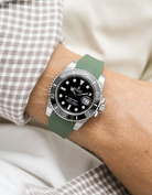 Wrist wearing a Rolex Submariner on a Wristbuddys FKM Rubber watch strap with a green strap and checkered shirt sleeve.