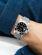 Rolex Submariner on a grey Wristbuddys FKM Rubber watch strap on a person's wrist with a blue shirt 