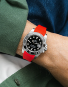 Rolex Submariner on a red Wristbuddys FKM Rubber watch strap on a wrist, wearing a green shirt.