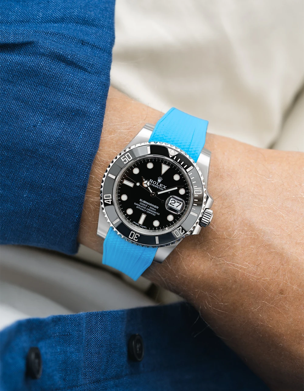 Rolex Submariner on a capri blue Wristbuddys FKM Rubber watch strap on a wrist, wearing a blue shirt.