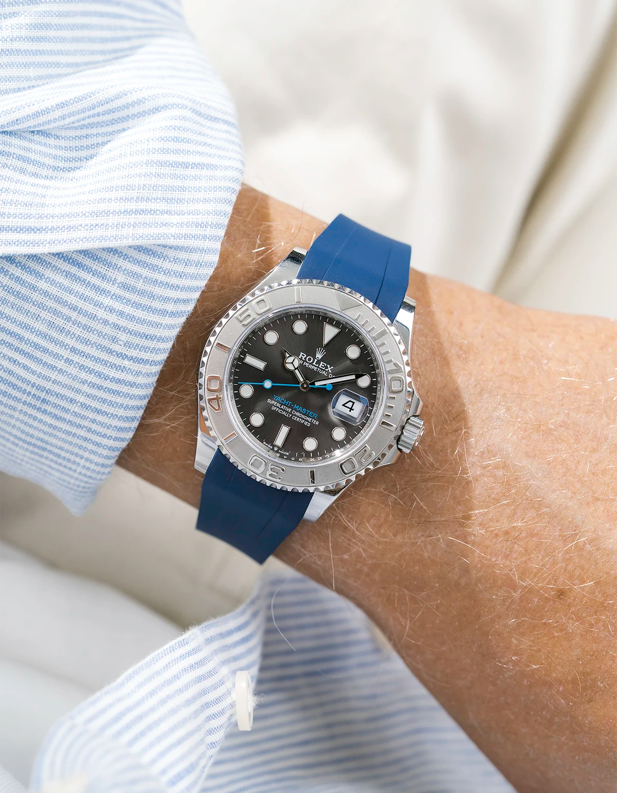 Close-up of a person wearing a Rolex YachtMaster 2 126622 / 116622 model watch with a light blue shirt sleeve and a blue FKM rubber watch strap from Wristbuddys