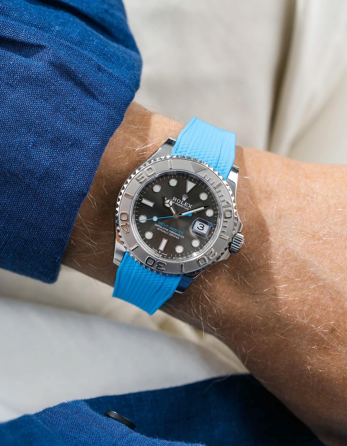 Close-up of a person wearing a Rolex YachtMaster 2 126622 / 116622 model watch with a blue shirt sleeve and a Capri Blue Vertech FKM rubber watch strap from Wristbuddys